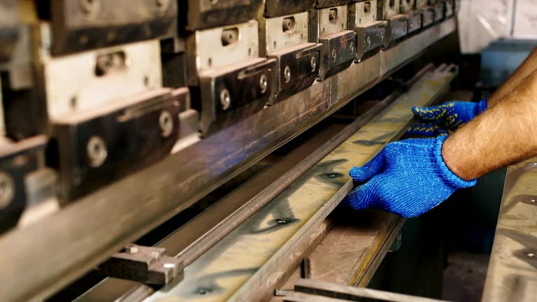 Hands of the worker with a metal workpiece. Supplies a part to a bending machine