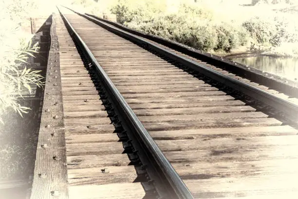 railroad tracks on a trestle crossing a river - travel concept, retro hand tinted opalotype processing