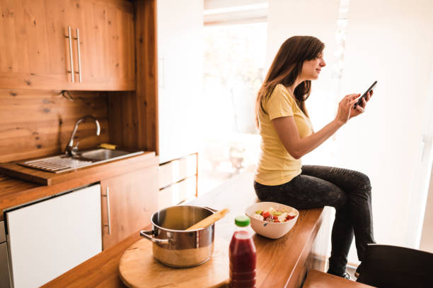 istock woman on the phone in the kitchen 672100798