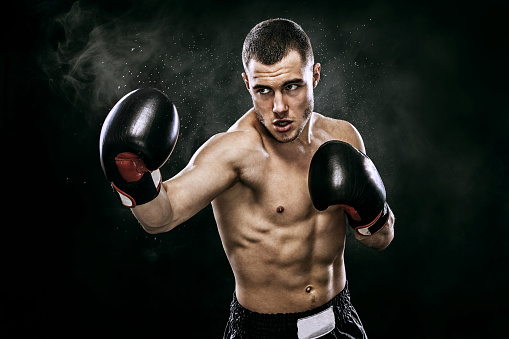 Street fighter fighting in boxing gloves. Isolated on black background with copy Space. Action shot. Sport concept.