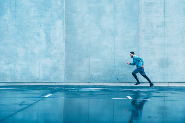 istock Man with sports clothes runs fast next to concrete wall 672116890