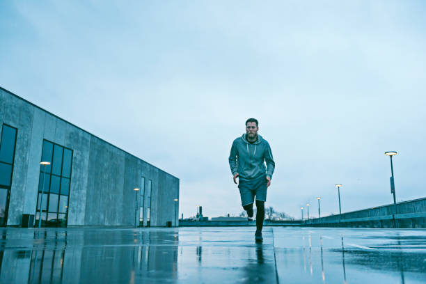 istock Male runner runs fast on wet streets on a grey day 672117024