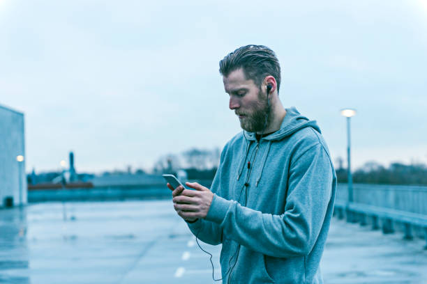 istock Male runner stands outside with mobile phone 672119070