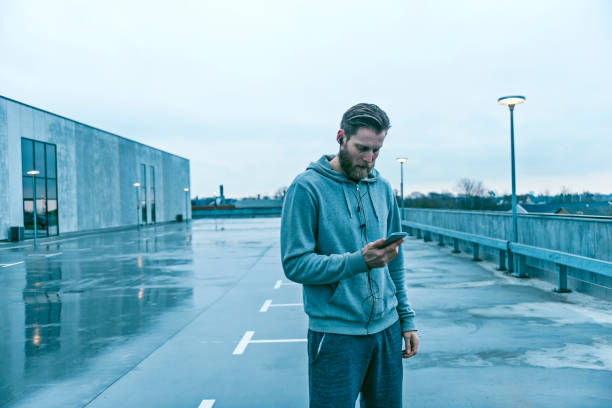 istock Male runner stands outside with mobile phone and headset 672119072