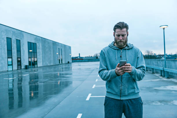 istock Runner wears headset and looks at his phone for a mobile app 672119080