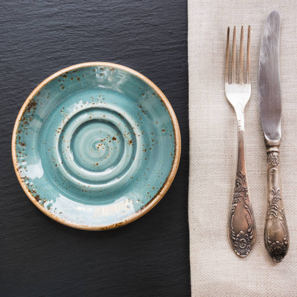 istock Rustic napkin, spoon and blue plate on black slate dish with cop 672140378