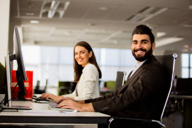 istock Man and woman sitting in office and smiling 672143484