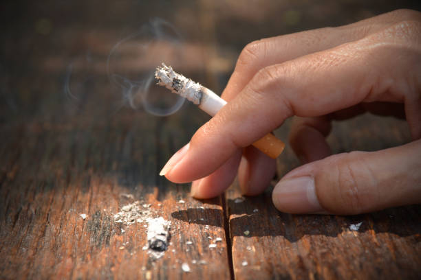 istock Tobacco cigarettes in hand on wooden background. 672146496