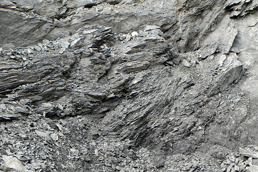 A very rough and irregular surface of a rock at a stone pit, the structured surface creates a wild and chaotic pattern or texture, resembling shale or granite.