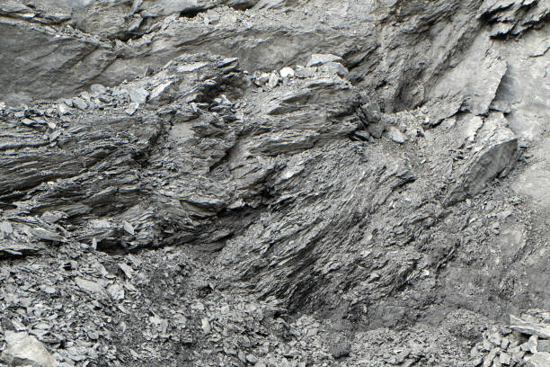 irregular pattern of a rock face at a quarry A very rough and irregular surface of a rock at a stone pit, the structured surface creates a wild and chaotic pattern or texture, resembling shale or granite. bedrock stock pictures, royalty-free photos & images