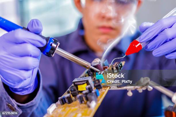 Engineer Or Technician Repair Electronic Circuit Board With Soldering Iron Stock Photo - Download Image Now