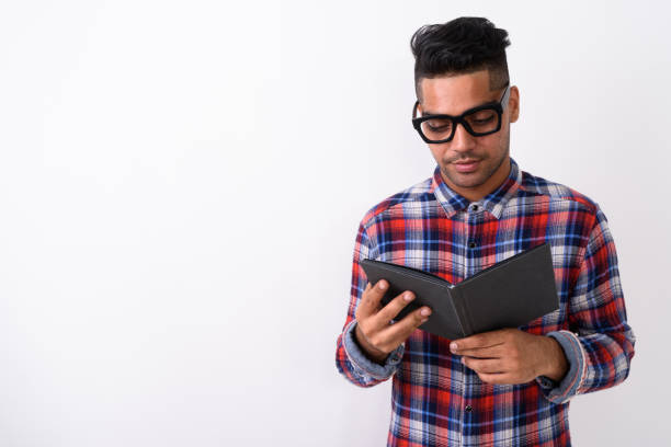 istock Studio shot of young Indian man reading book while wearing eyeglasses against white background 672153768