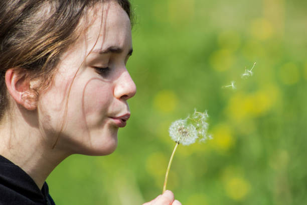 istock Girl blowing flower 672156394