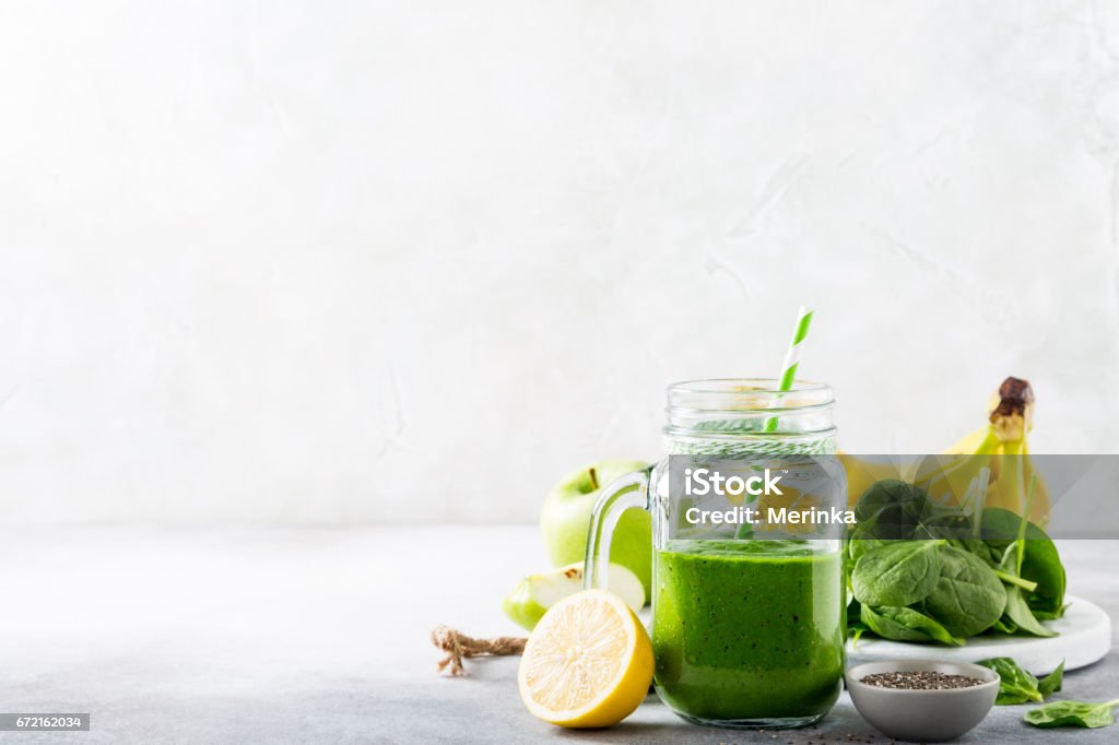 Healthy green smoothie with spinach in glass jar Healthy breakfast with green smoothie in glass jar and ingredients. Detox, diet, healthy, vegetarian food concept with copy space. Smoothie Stock Photo
