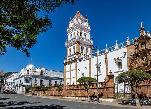 Captured on a radiant sunny afternoon, this image showcases the magnificent exterior of the Inmaculada Concepción Church in Barranquilla, Colombia. The church, a historical and religious landmark, stands proudly under the expansive blue skies. Its gothic-style architecture is highlighted by the ornate facade, intricate stonework, and the presence of stunning stained glass windows that add a colorful vibrancy. The architectural symmetry is evident, with each arch and column meticulously designed, reflecting the church's grandeur and elegance.