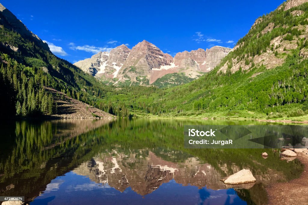 Maroon Bells Lake Reflections in Summer The famous Maroon Bells reflections on a still standing water of the lake early in the morning in summer. Maroon Bells Stock Photo