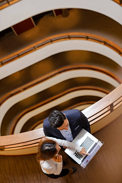 istock Two Business People Standing in the office building  and Using Laptop 672185684