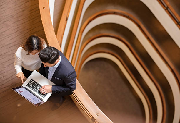 istock Two Business People Standing in the office building  and Using Laptop 672185786