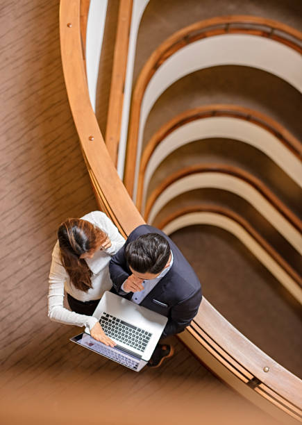 istock Two Business People Standing in the office building  and Using Laptop 672187874