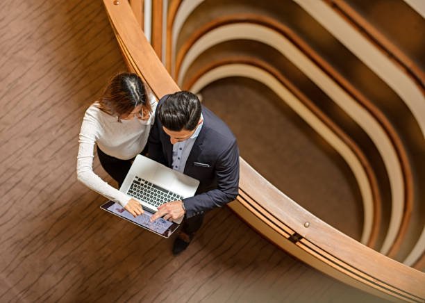 istock Two Business People Standing in the office building  and Using Laptop 672187948