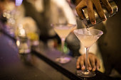 Hands of a Panamanian bartender pouring dirty martini into a glass.