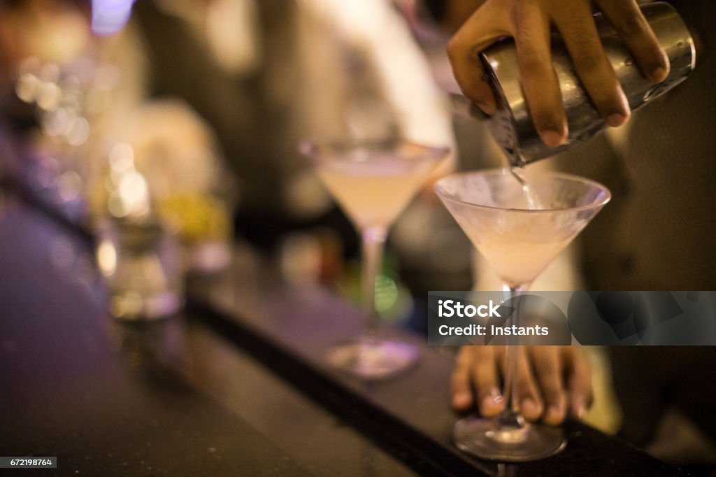 Hands of a Panamanian bartender pouring dirty martini into a glass. Alcoholic beverage. Martini Stock Photo