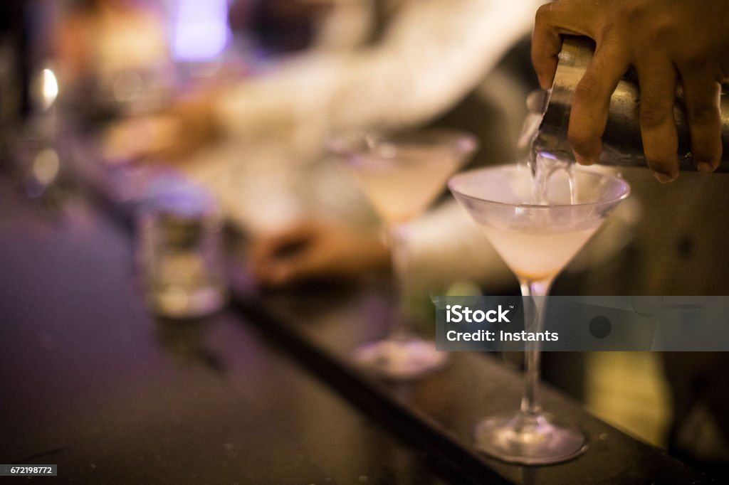 Hands of a Panamanian bartender pouring dirty martini into a glass. Alcoholic beverage. Dirty Martini Stock Photo
