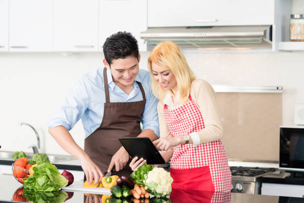 istock Asian couple cooking after recipes from tablet computer 672216838