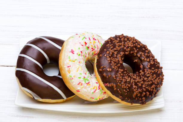 istock Tasty bitten donuts with icing and chocolate on white wooden background, copy space 672222798