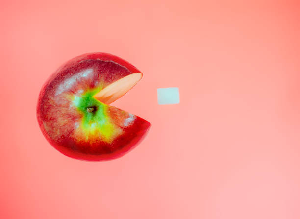Creative idea with apple like character computer game pacman on red pastel background. Art food concept