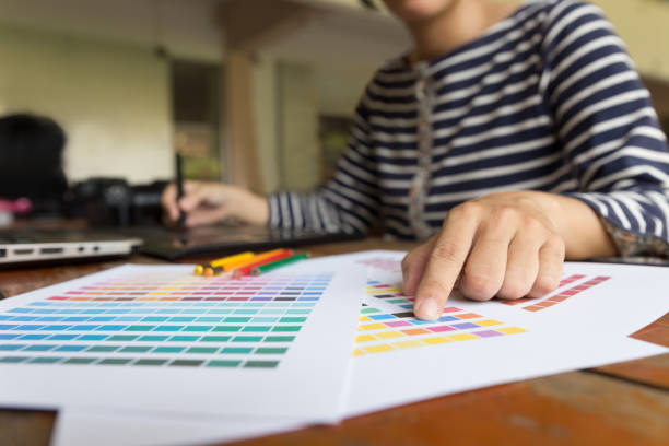 istock freelance graphic designer using digital tablet, computer, woman working with color swatch catalog samples for selection - Creativity Editor Ideas Designer Concept 672237164