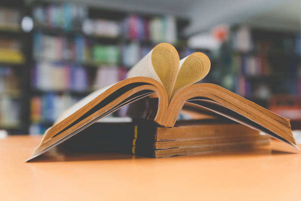 istock old book page in heart shape with library background, love in valentine day 672237314