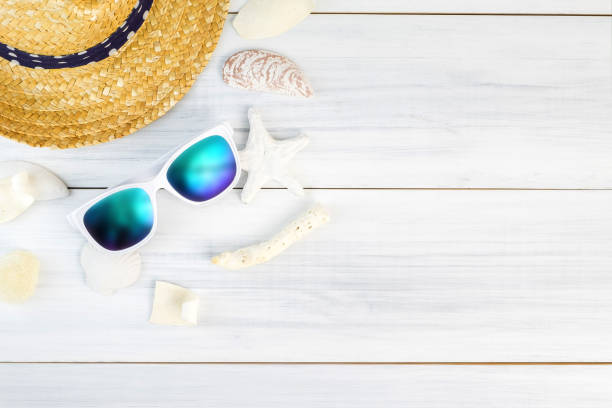 istock Summer Beach accessories (White sunglasses,starfish,straw hat,shell) on white plaster wood table top view,Summer vacation concept,Leave space for adding text 672237378