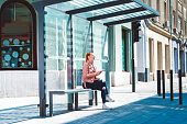 Beautiful young student at the glass made bus shelter