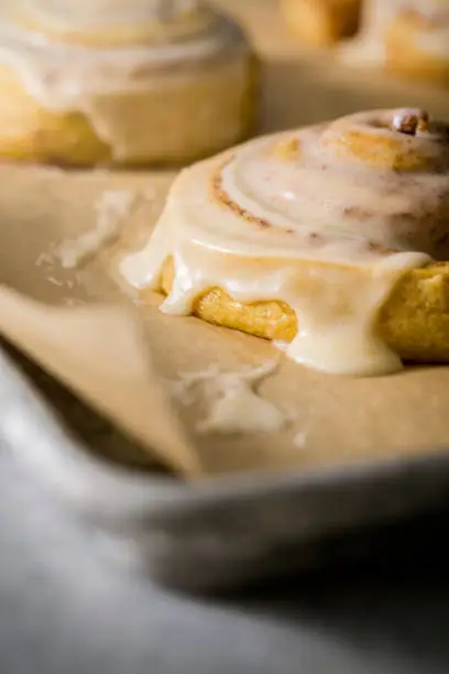 Fresh hot cinnamon bun / sticky bun with icing on baking sheet fresh from the oven.