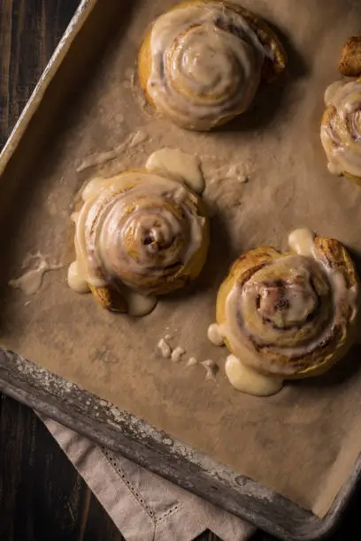 Fresh hot cinnamon bun / sticky bun with icing on baking sheet fresh from the oven.