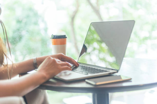 istock Side view of female hands using laptop with coffee and smartphone beside 672268778