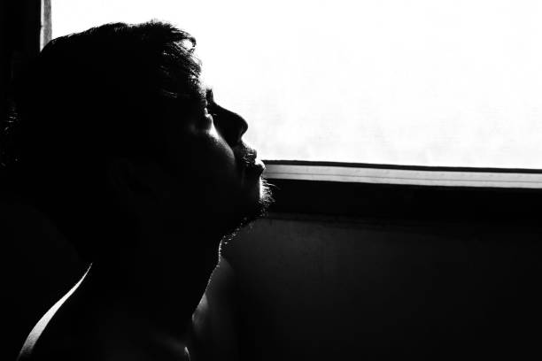 istock depressed and hopeless man alone in the room with window 672281792