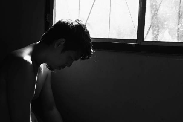 istock depressed and hopeless man alone in the room with window 672284174