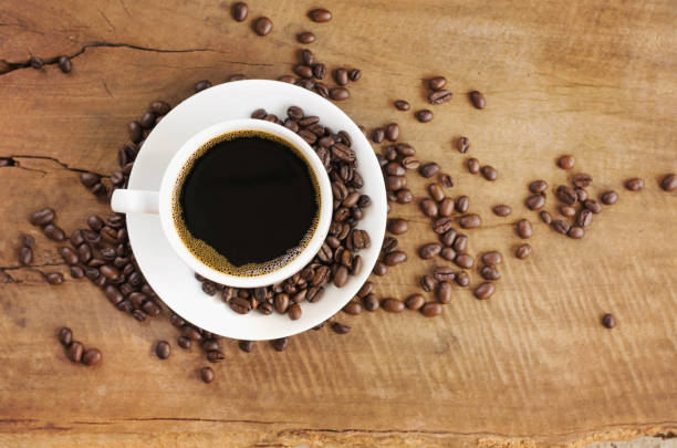 istock Coffee cup and coffee beans on wooden background. Top view 672285146