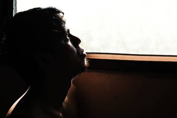 istock depressed and hopeless man alone in the room with window 672287256
