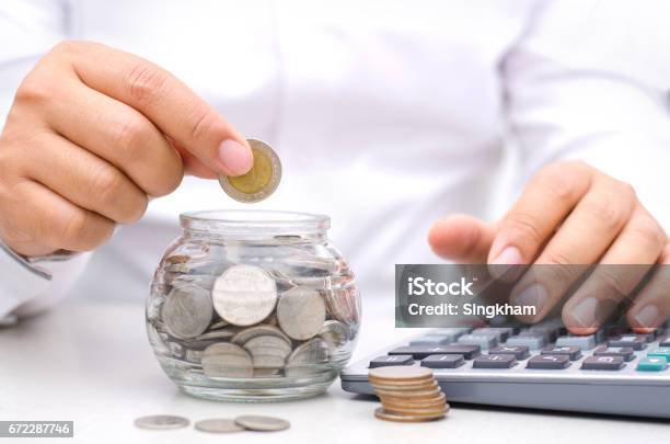 Male Hand Putting Money Coins Into Glass Jar Bank Stock Photo - Download Image Now - Accountancy, Adult, Banking