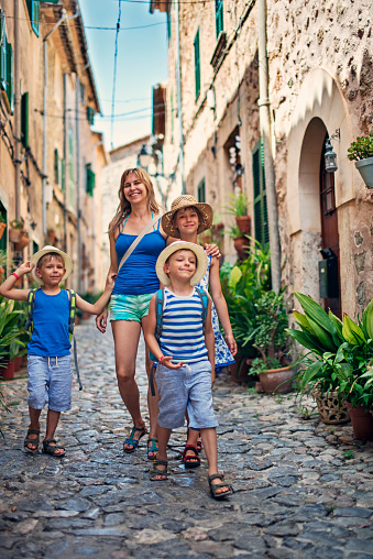 Mother with three kids tourists visiting the beautiful majorcan town. \n\n