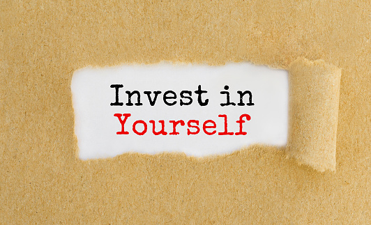 Text Invest in Yourself appearing behind ripped brown paper.