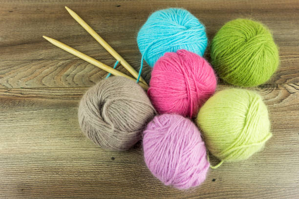 istock Colored wool balls with needles on a rustic wooden table 672308942