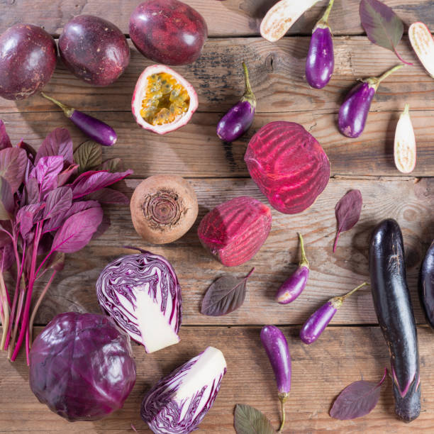 Collection of fresh purple fruit and vegetables on wooden background.