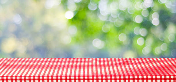 istock Empty table with red tablecloth over blur green tree and bokeh background, for food and product display montage background, banner 672309916