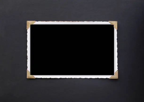 Photo of Photo frame - real old photo with black blank space for copy photo pasted with gold coloured photo holder corners onto black vintage album paper page - Photograph