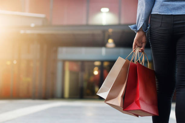 woman walking with shopping bags on shopping mall background - shopping bag imagens e fotografias de stock