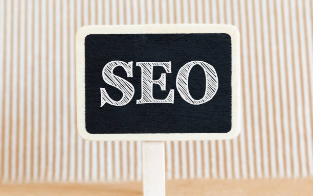 istock Handwritten text SEO with white chalk on a blackboard on a paper background 672313102